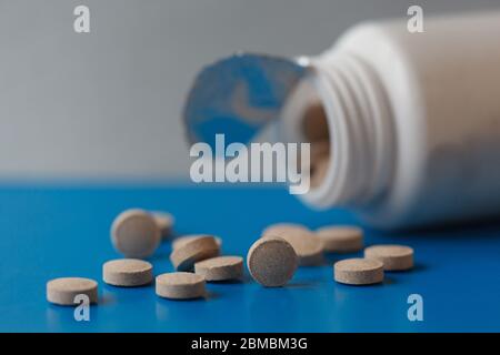 Bierhefe-Tabletten. Nahrungsergänzungsmittel. Pillen aus einem Glas auf blauem Hintergrund gegossen. Stockfoto