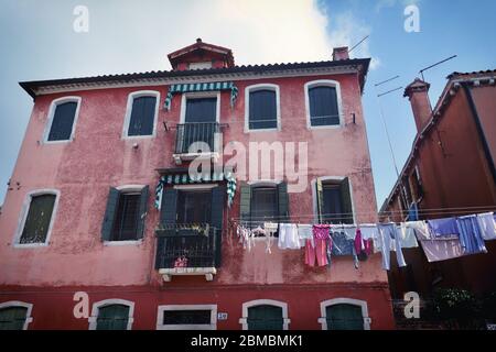 Wäsche trocknet aus, hängt an einer Wäscheleine zwischen zwei Gebäuden in Murano, Italien Stockfoto