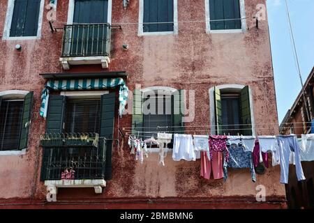 Wäsche trocknet aus, hängt an einer Wäscheleine zwischen zwei Gebäuden in Murano, Italien Stockfoto