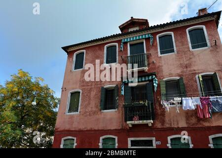 Wäsche trocknet aus, hängt an einer Wäscheleine zwischen zwei Gebäuden in Murano, Italien Stockfoto