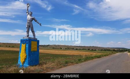 Sowjetische Kunststatue des Arbeiters in mächtiger Pose mit Himmel Hintergrund. Sozialrealismus Denkmal in Odessa Landschaft der Ukraine Stockfoto