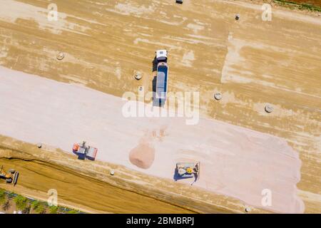 Luftaufnahme von Bulldozer gießt Sand in den LKW. Auf der Baustelle von oben. Schießen von der Drohne. Stockfoto