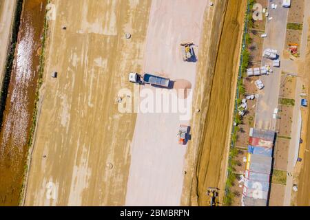 Luftaufnahme von Bulldozer gießt Sand in den LKW. Auf der Baustelle von oben. Schießen von der Drohne. Stockfoto