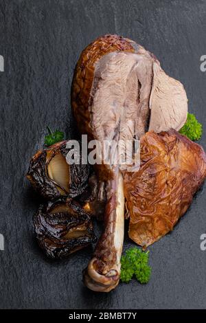 Geröstete putenschenkel mit gebackenen Zwiebeln auf schwarzem Steingrund Stockfoto