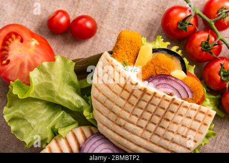 Pita Döner Kebab mit grünem Salat, Tomaten Kirsche, Kartoffel frei, gegrillte Fischstäbchen . Street Food. Fast Food. Döner Kebab Stockfoto