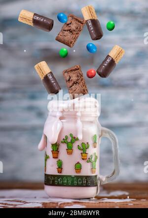 Rosa Erdbeere Freakshake mit Süßigkeiten in der Luft fallen Stockfoto