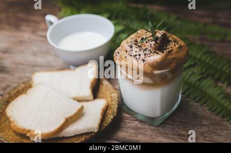 Dalgona Kaffee trendy koreanischen Stil auf Holzplatte mit Garten Außenbeleuchtung. Stockfoto