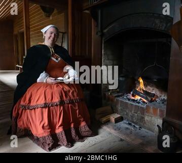 Ballarat, Australien - 7. März 2020: Eine Frau in traditioneller Kleidung, die in einer nachgebildeten Bergarbeiterstadt am Kamin mit einem Teller Pfannkuchen sitzt Stockfoto