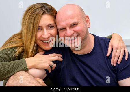 Glücklich liebenden mittleren Alters Paar mit Armen um einander genießen kostbare Zeit zusammen und lächeln, schauen und lachen direkt in die Kamera Stockfoto