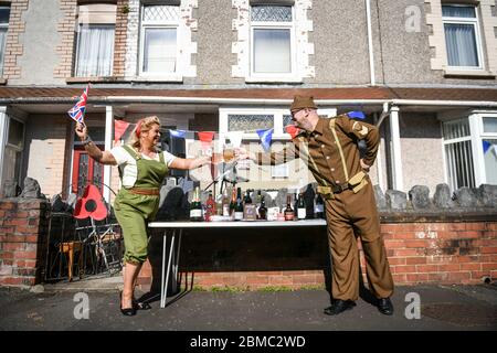 Swansea, Wales, Großbritannien. Mai 2020. Michael und Janet Roberts trinken gemeinsam mit der sozialen Distanz außerhalb ihres Hauses in der Cecil Street in Swansea, Wales, in Vintage-Kleidung, während der VE Day-Feierlichkeiten der Straße. Quelle: Robert Melen/Alamy Live News. Stockfoto