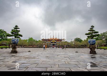 Hue, Vietnam - 15. April 2018: Einige Touristen betreten den Haupthof der Hue-Zitadelle hinter dem Haupttor, mit einem bewölkten Himmel Stockfoto