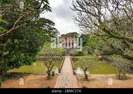 Hue, Vietnam - 16. April 2018: Einer der Pavillons des Minh Mang Grab mit sehr wenigen Touristen und einem bewölkten Himmel Stockfoto