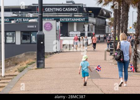 Ein Kind und eine Mutter laufen am 75. Jahrestag des VE Day auf Southend an der Seeseite mit Union Jack-Flaggen während der COVID-19-Sperrung. Familie im Freien Stockfoto