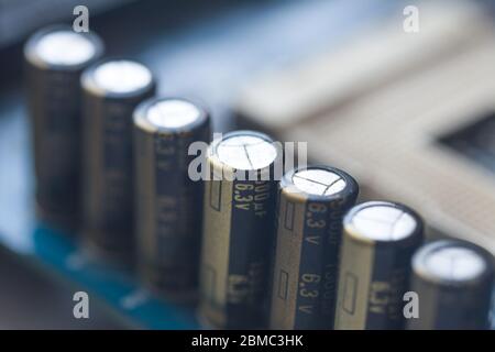 Fragment der Hauptplatine mit Elektrolytkondensatoren. Kapazitive Baugruppe. Kondensator für elektronische Bauteile auf der blauen Leiterplatte Stockfoto