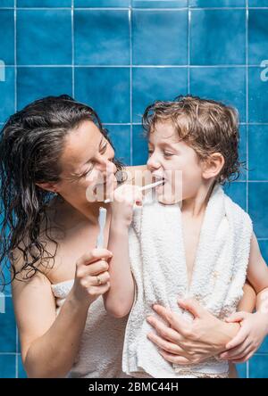 Eine Frau und ein Kind putzen sich mit blauen Kacheln im Hintergrund die Zähne. Stockfoto