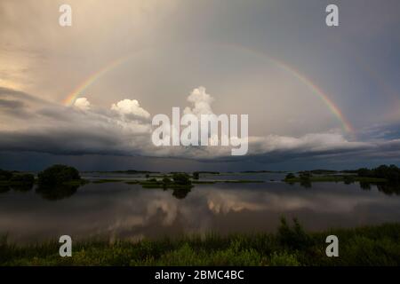 Voller Regenbogen über Sturmwolken Stockfoto