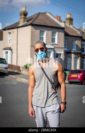 West Norwood, Großbritannien. Mai 2020. Ein junger Mann trägt eine schützende Gesichtsmaske und Sonnenbrille mit grauer Weste und Trainingsanzug-Hose zum 75. Jahrestag des VE Day in South London, England. (Foto von Sam Mellish / Alamy Live News) Stockfoto