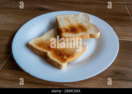 2 Scheiben Weißes geröstetes Brot auf weißem Teller. Kochen Sie ein leckeres Frühstück zu Hause. Stockfoto