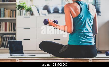 Home Workout Konzept Frau im Wohnzimmer mit Laptop und Hanteln psychische Gesundheit in Quarantäne Stockfoto