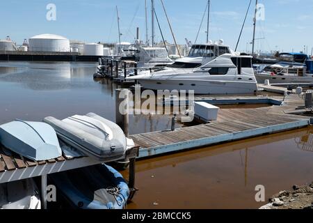 Extrem verschmutztes Wasser in einem Bootshafen in der Nähe von Öllagertanks Stockfoto