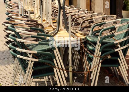 Tische und Stühle eines Restaurants gestapelt und verkettet. Letzte Tage des Aufenthalts zu Hause Ordnung in Meran, Italien. Phase 2 von COVID-19. Stockfoto