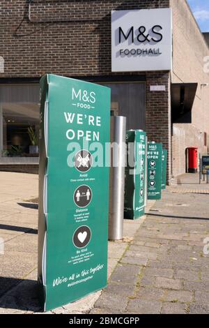 Wir sind offene Schilder vor M&S Foodhall mit Rat für soziale Distanz und halten 2 m von anderen während Covid-19 entfernt. Basingstoke, Großbritannien. Mai 2020 Stockfoto