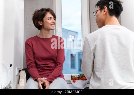 Foto von lächelndem multinationalen Paar mit Handy und Kochen Abendessen in der Küche zu Hause Stockfoto