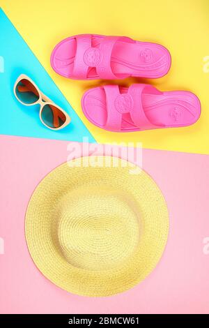 Hut, Sonnenbrille und Hausschuhe auf drei - Farbe Pastell Hintergrund Blau, Gelb und Pink Stockfoto