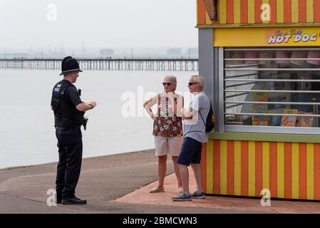 Polizeibeamter, der während der COVID-19-Coronavirus-Sperrzeit mit Menschen an der Küste von Southend am VE Day Bankfeiertag spricht. Schließen Sie den Hot-Dog-Stand Stockfoto