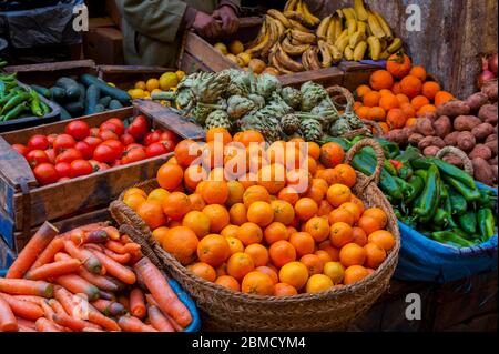 Eine Straßenszene mit Orangen, Karotten, Paprika, Tomaten, Bananen, Artischocken und anderen Produkten, die in einer kleinen Gasse in der Medina (Altstadt) verkauft werden Stockfoto