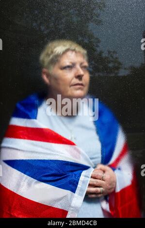 Frau drapiert Union Jack Flagge über ihre Schultern hinter Glas Am St. Georges Day Stockfoto