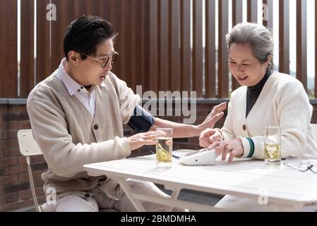 Ein asiatisches älteres Paar misst den Blutdruck Stockfoto