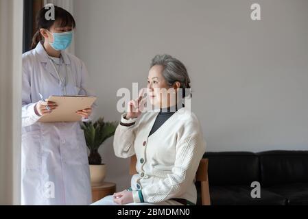 Der junge Hausarzt spricht mit Senioren Stockfoto