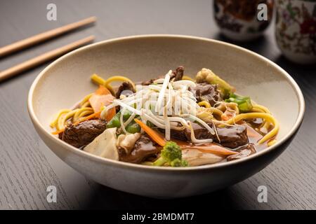 Fleisch Filet Yakisoba auf einer Schüssel - Nudeln mit Gemüse mit Sojasauce auf einem verschwommenen Hintergrund Stockfoto