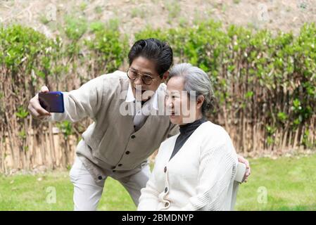 Ein asiatisches älteres Paar benutzt ein Mobiltelefon, um Selfies zu machen Stockfoto