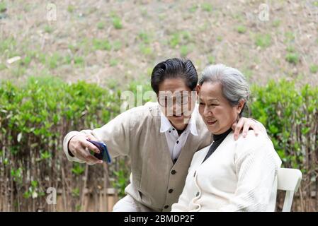 Ein asiatisches älteres Paar benutzt ein Mobiltelefon, um Selfies zu machen Stockfoto