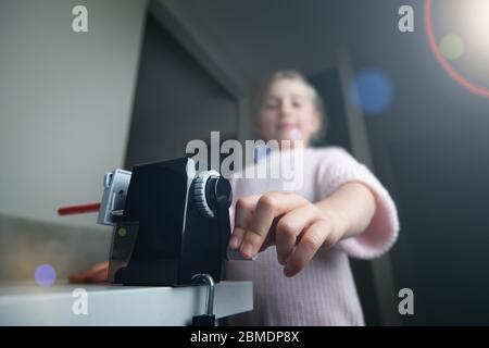 Junges Mädchen mit Bleistiftspitzer zu Hause Stockfoto