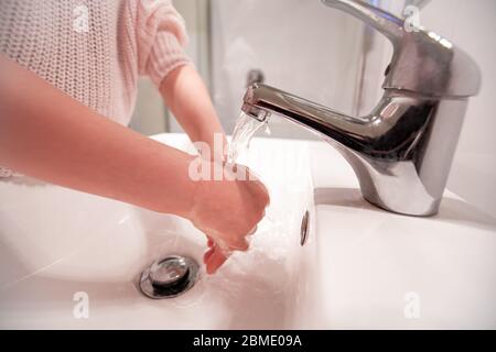 Kinder waschen ihre Hände unter fließendem Wasser. Vermeiden Sie die