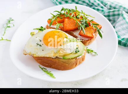 Gesundes Frühstück. Sandwich mit Avocado und Spiegelei, Sandwich mit gebratenem Kürbis in Scheiben für gesundes Frühstück oder Snack. Stockfoto