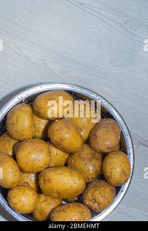 Rohe Kartoffeln in einer eisernen Schüssel auf hellem Hintergrund Stockfoto