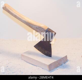 Alte Axt in einem Log auf hellem Hintergrund. Stockfoto