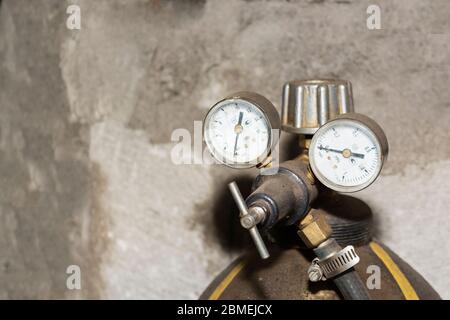 Nahaufnahme einer Gasflasche aus Metall mit Untersetzungsgetriebe und Ein Drucksensor in der Industriewerkstatt im Hintergrund Stockfoto