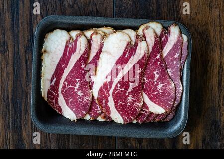 Roh geräuchert trocken gereiften Kalbsrippe Scheiben in Kunststoff-Container-Box-Paket zum Verkauf. In Scheiben geschnitten und geschnitten Schinken / Salami. Bereit zum Essen. Stockfoto