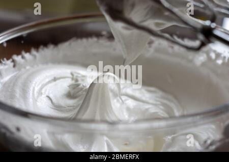 Weiche Baiser-Gipfel frisch mit dem Baiser, der die klassischen steifen Gipfel bildet, geflüstert. Der Mixer ist oben, was zeigt, dass der Baiser mi beendet hat Stockfoto