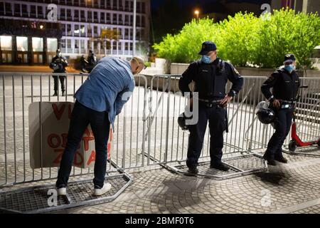 Ljubljana, Slowenien, 8. Mai 2020: Ein Protestler passt auf ein Pappschild, während zwei Polizisten während eines Anti-Regierungs-Protests inmitten der Coronavirus-Krise zusehen. Stockfoto