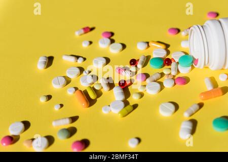 Pillen auf gelbem Hintergrund isoliert.Tabletten und Kapseln.Gesundheitswesen und medizinische Medikamente Konzept mit einer Nahaufnahme auf Pillen verschüttet aus einem Rezept Stockfoto