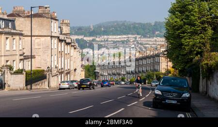 Bath, England, UK - 20. April 2011: Ein Radfahrer fährt auf dem steilen Bathwick Hill vorbei an den georgischen Häusern und dem Stadtbild von Bath in Somerset. Stockfoto