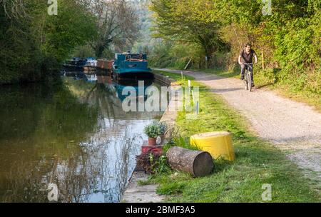 Bath, England - 19. April 2011: Ein Radfahrer, der vorbeifahrenden Boote auf dem Treidelpfad Kennet & Avon Canal in der Nähe von Bath in Somerset. Stockfoto