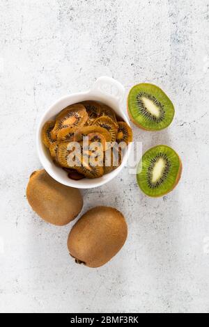 Kiwi-Chips. Getrocknete Scheiben auf einer hellen Oberfläche, vertikale Ausrichtung Stockfoto