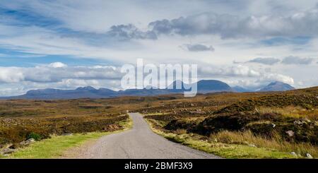 Eine schmale Gasse windet sich durch die Moorlandschaft der Applecross-Halbinsel, hinter der die hohen Berge der Torridon Hills und des Shieldaig Forest emporragen. Stockfoto